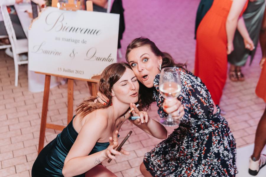 Deux amies font la fête devant le panneau d'accueil d'un mariage