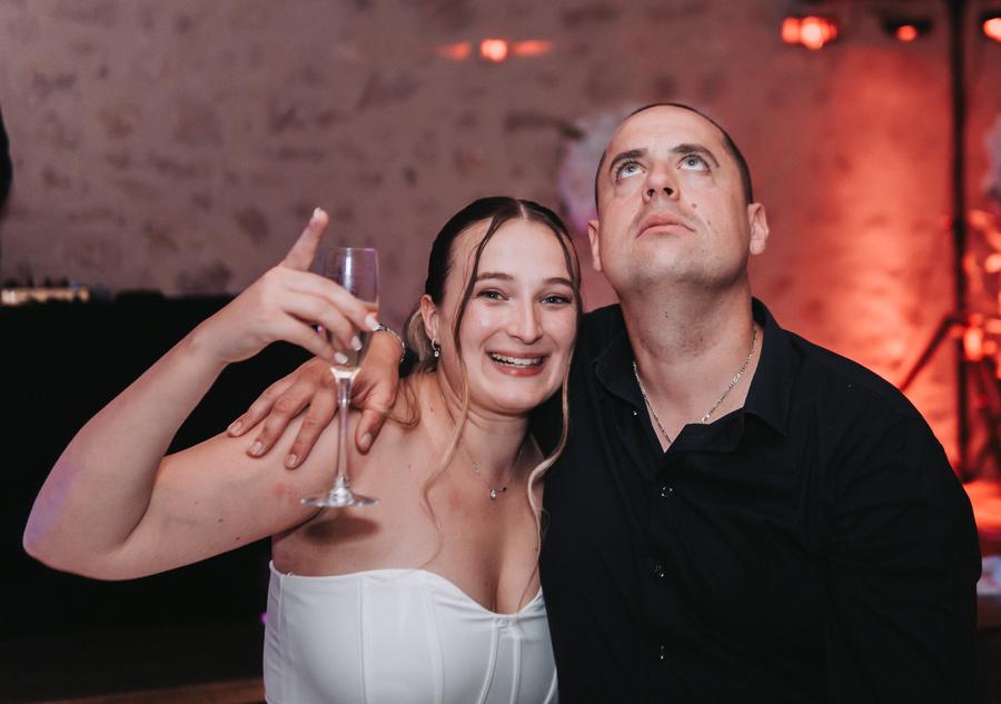 Une invitée lève son verre, assise à côté d'un ami