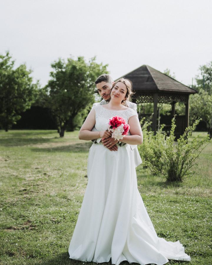 La mariée sourit, son bouquet de pivoines à la main