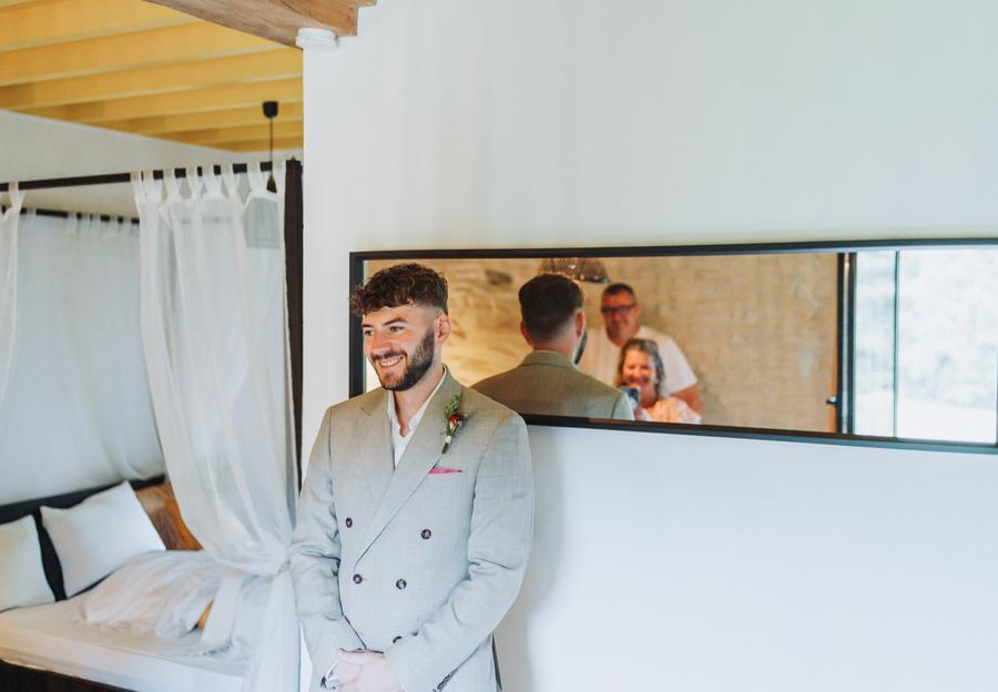 Le marié sourit pendant la découverte, ses proches dans le miroir