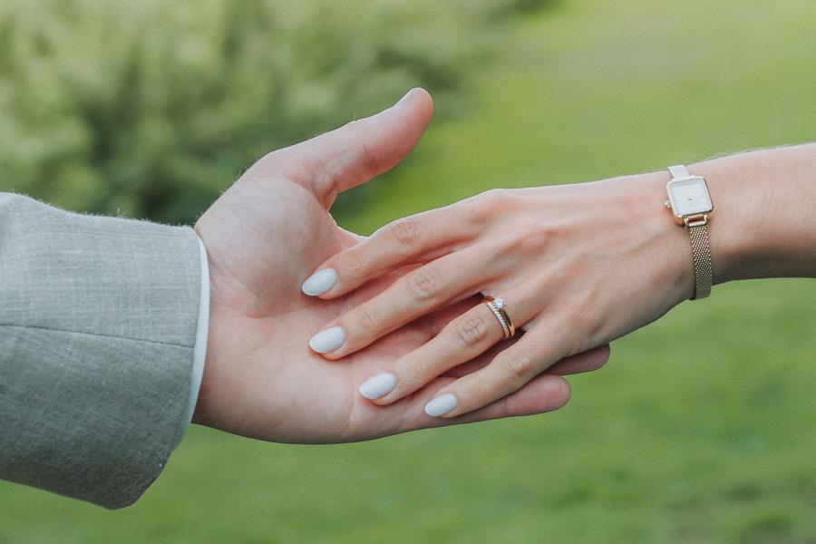 La main de la mariée posée dans celle du marié, bague et montre
