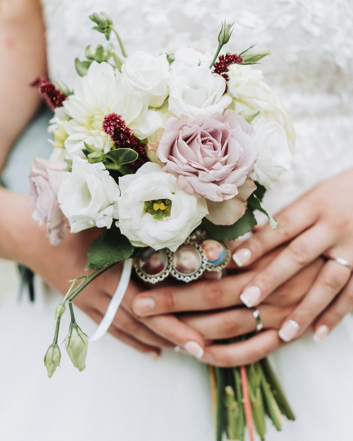 Les mains de la mariée tenant son bouquet de roses