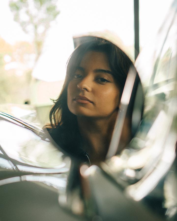 Reflet d'une jeune femme dans le rétroviseur chromé