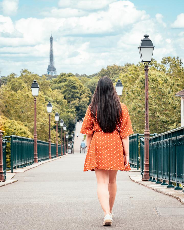 Femme en robe orange marchant sur une passerelle à Paris