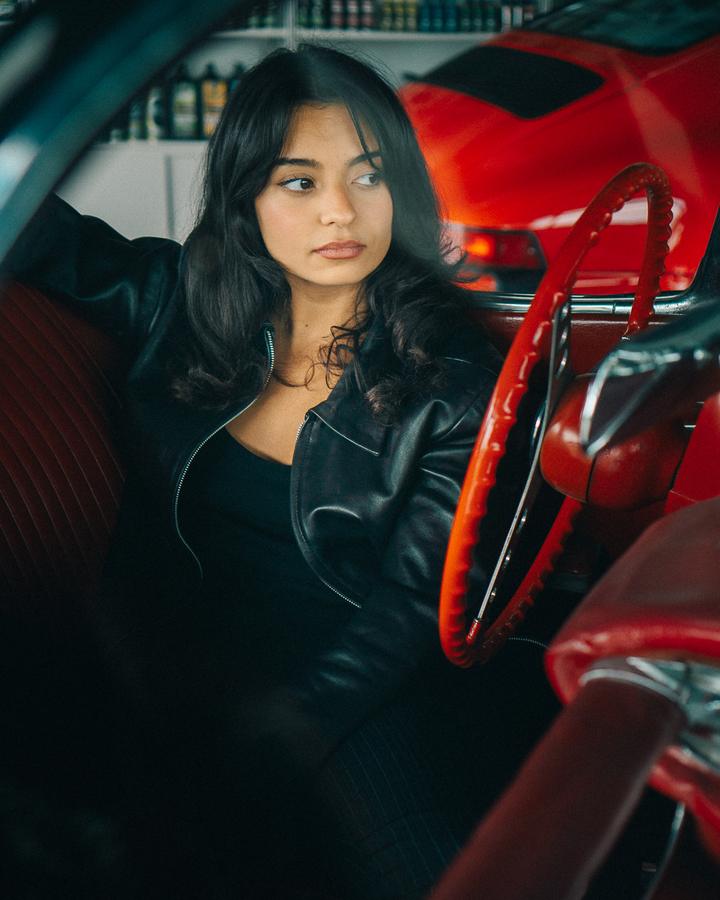 Jeune femme au volant d'une voiture ancienne rouge