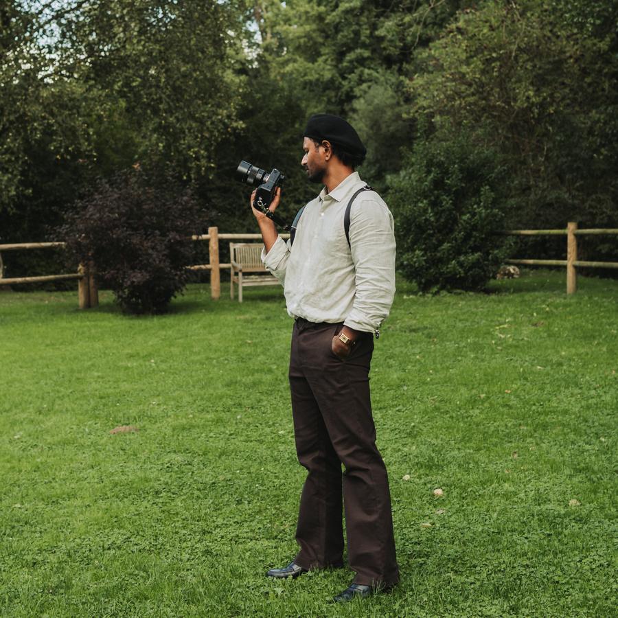 Adavan, photographe, son appareil à la main dans un jardin