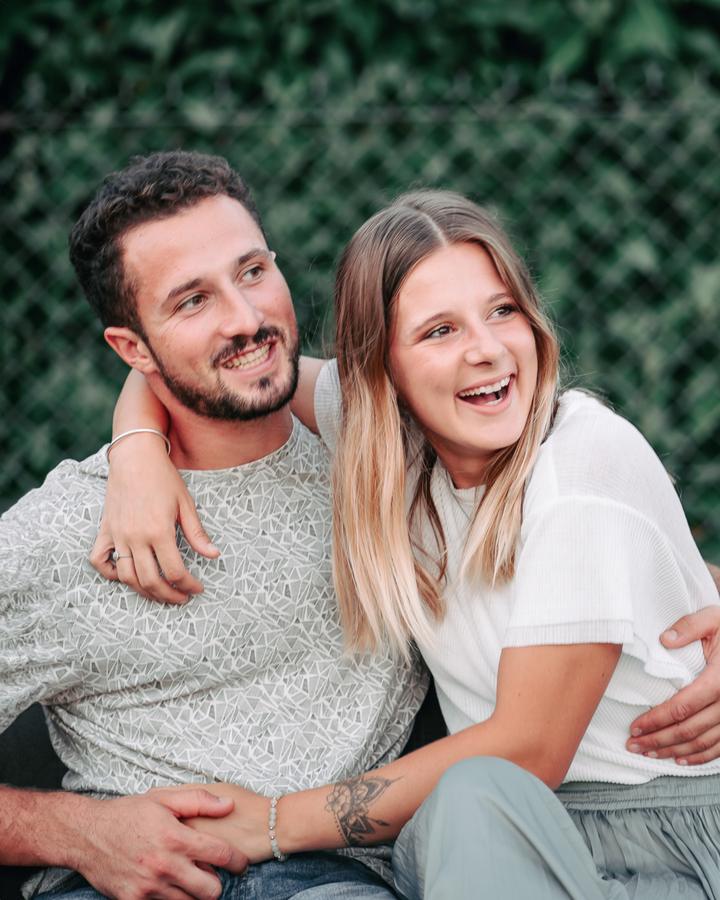 Couple qui rit, enlacé devant un mur végétal